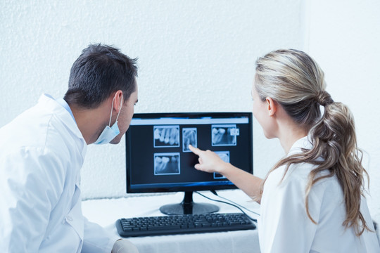在电脑上看X光片的两名牙科医生