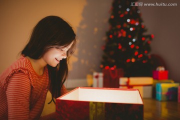 小女孩打开一个发光的圣诞礼物