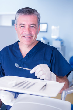 微笑着拿着牙科工具的牙医