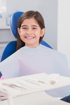 坐在牙科椅上微笑着的病人