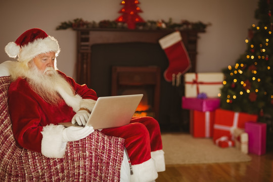 坐在沙发上使用电脑的圣诞老人