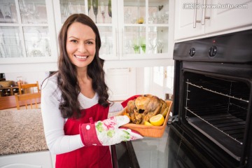 微笑的女人从烤箱中拿出烤火鸡
