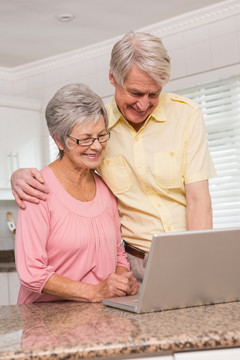 在客厅里使用笔记电脑的老夫妇