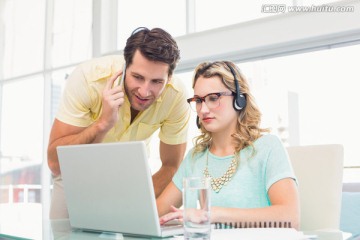 看着笔记本电脑讨论的商务男女
