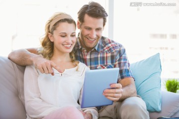 年轻夫妇在沙发上使用平板电脑