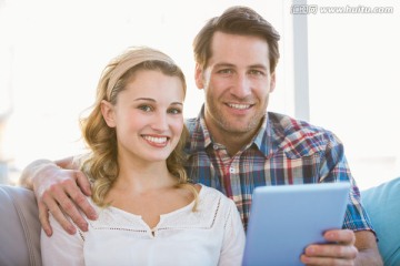 年轻夫妇在沙发上使用平板电脑
