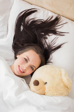 抱着泰迪熊躺在床上的女人