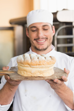 微笑的男面包师拿着一个面包
