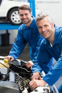 微笑的两名汽车修理工在修汽车