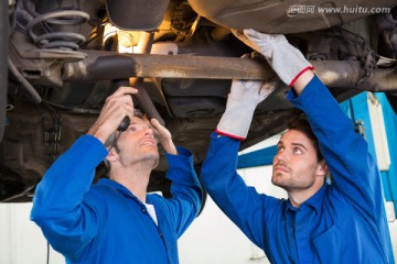 在修理汽车底部的两名修理工