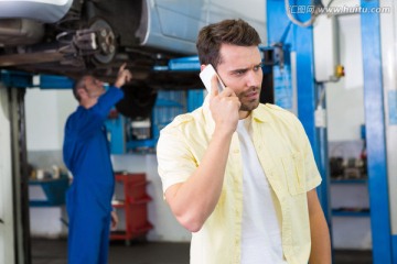 在汽车维修厂打电话的男客户