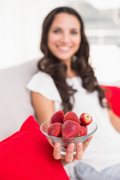 坐在沙发上的女人拿着一碗草莓