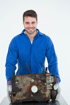 微笑的男机械师拿着旧汽车发动机