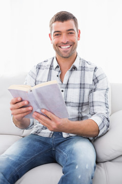微笑的男人坐在沙发上看书