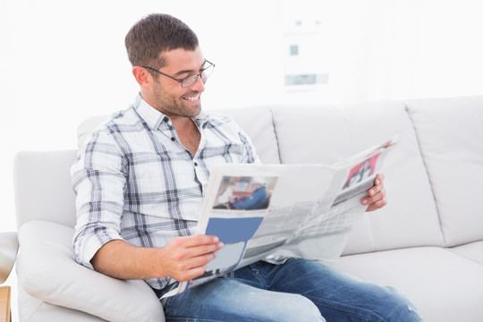 坐在家里的沙发上看报纸的男人