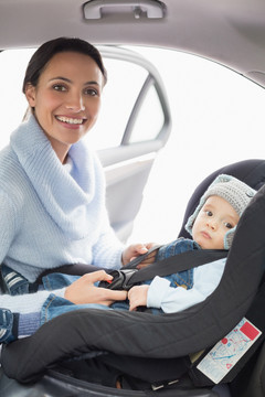 在车上给婴儿系安全带的母亲