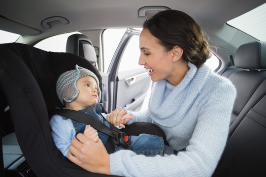 在车上给婴儿系安全带的母亲