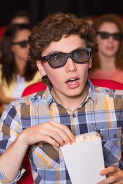 在电影院里看电影吃爆米花的男人