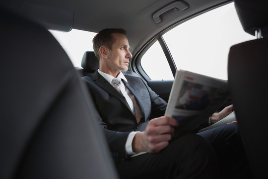 坐在车上看报纸的商务男人