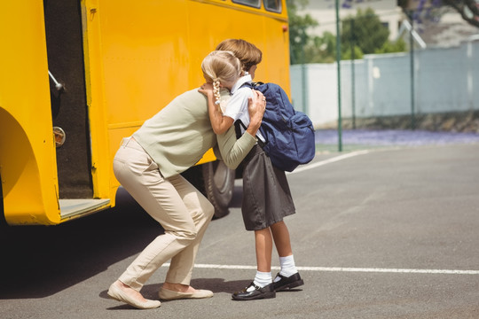母亲抱着女儿乘校车上学