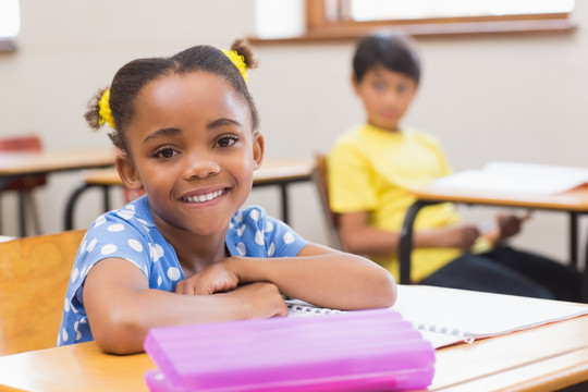 微笑的小学生坐在课桌旁