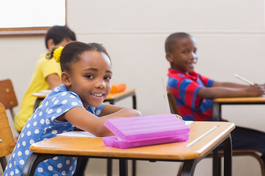 微笑的小学生坐在小学的课桌旁