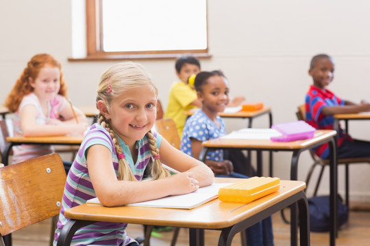 微笑的小学生坐在小学的课桌旁