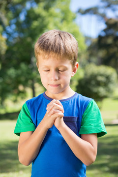 小男孩在阳光明媚的日子里祈祷