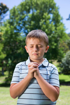 小男孩在阳光明媚的日子里祈祷