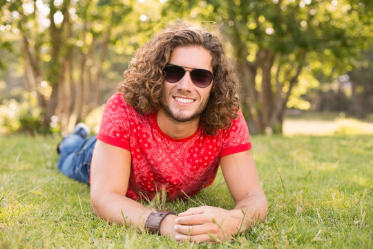 微笑的男人趴在公园草坪上