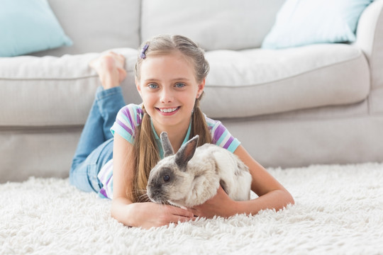 趴在地毯上抱着兔子的小女孩