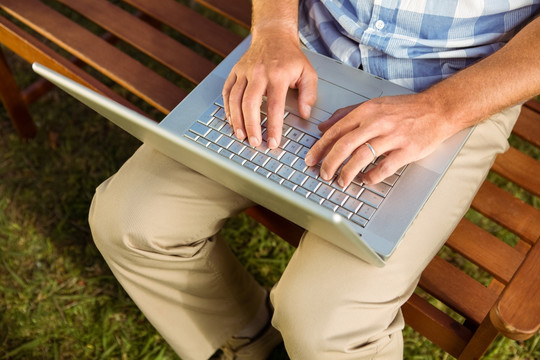 坐在长凳上使用笔记本电脑的男人