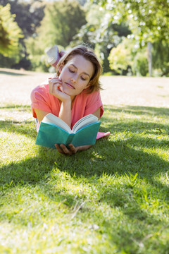 趴在公园草坪上看书的女人