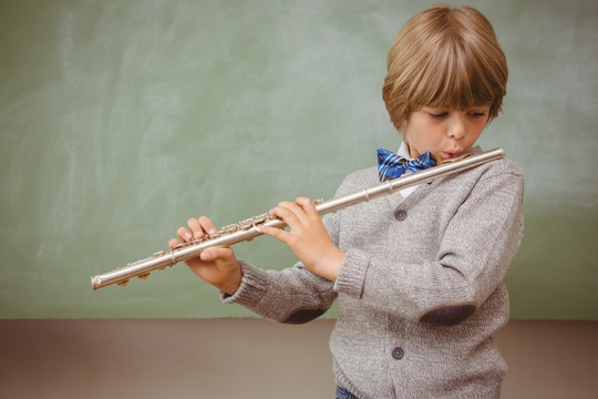 可爱的小男孩在教室里吹长笛