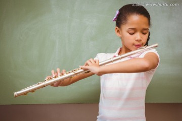可爱的小女孩在教室里吹长笛