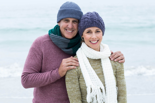 夫妇戴着围巾和帽子在海滩上