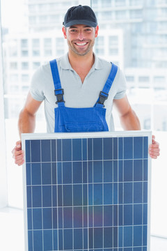 微笑着拿着太阳能电池板的男人
