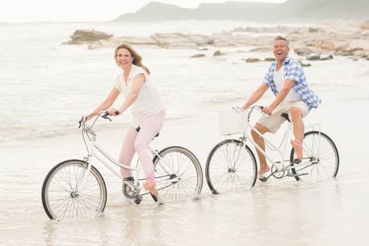 在海边骑自行车的夫妇