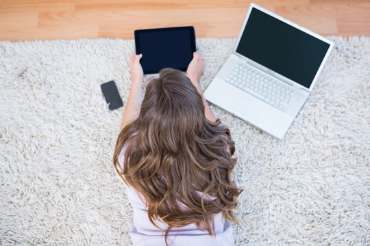 趴在地毯上使用平板电脑的女人