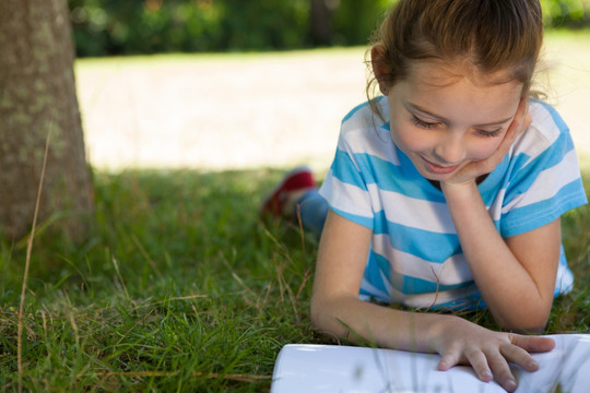 趴在草坪上看书的小女孩