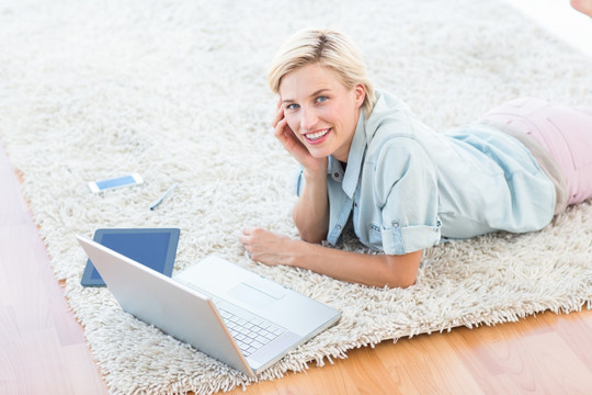 趴在地毯上用笔记本电脑的女人
