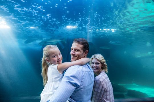 在水族馆微笑着看鱼的一家人