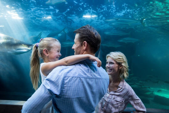 在水族馆微笑着看鱼的一家人