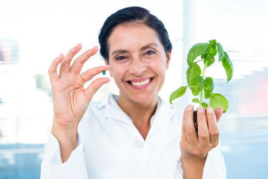 女人拿着植物和药丸