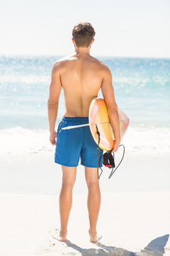 在海边拿着冲浪板的男人