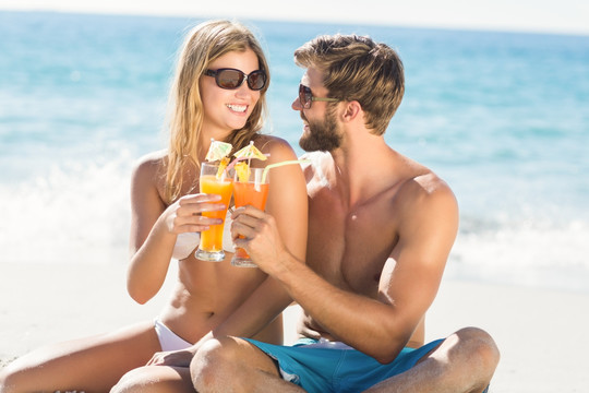 坐在沙滩上喝鸡尾酒的一对夫妇