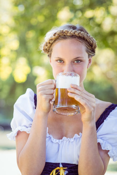 漂亮的金发女人在公园喝啤酒