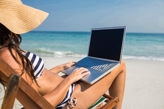 坐在海边用电脑的女人