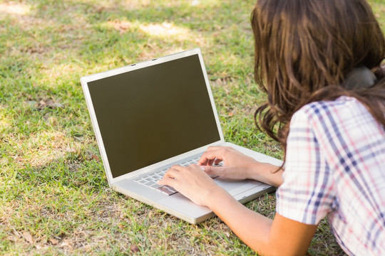 趴在草坪上用笔记本电脑的女人