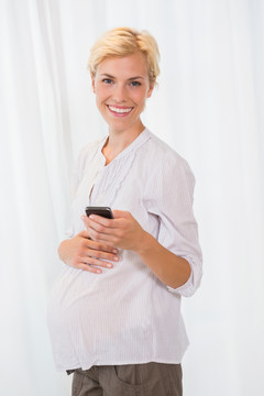 微笑着使用手机的孕妇